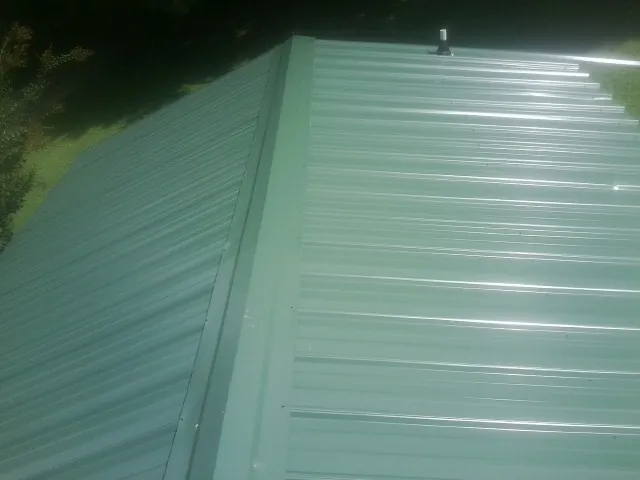 New green metal panels meeting at the ridge of a roof — Flat Roof Repair work by our crew in East Palatka