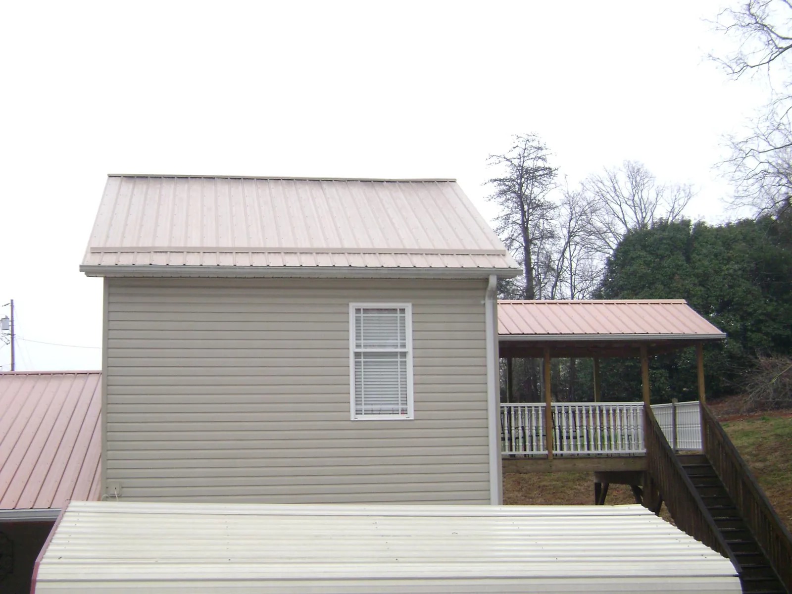 Tan metal roofs on a two story addition and attached porch, from a Roof Replacement job in East Palatka