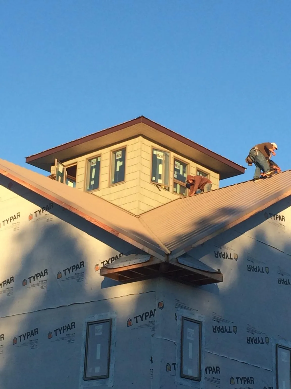 Roofers working around a rooftop cupola on a new metal roof at sunset — Roof Waterproofing in East Palatka by Roofing Brothers